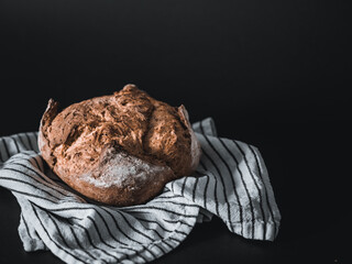 Homemade bread on a striped doily napkin on a dark background copy space.