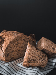 Bread, traditional sourdough bread cut into slices on a dark background. Healthy food.