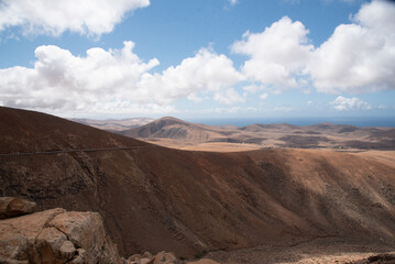 Vista panorámica de un impresionante paisaje montañoso y desértico con grandes montañas volcánicas inactivas y el mar de fondo en un día soleado en Fuerteventura, Islas Canarias.