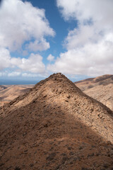 Paisaje volcánico y desértico con una gran montaña rocosa puntiaguda en el medio durante un día soleado con un cielo azul claro en Fuerteventura, Islas Canarias.