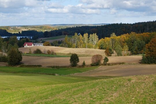 Beautiful scenery of kashubian landscape with fields and trees on hills in autumn scenery. Little houses  among fields. Around Sierakowice, Kashubia, Poland