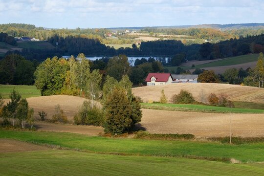 Beautiful scenery of kashubian landscape with fields and trees on hills in autumn scenery. Little houses  among fields. Around Sierakowice, Kashubia, Poland