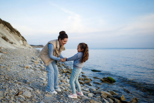 family weekend by the sea. happy mother and daughter have fun on a walk. sunset on the sea