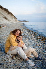 Fototapeta premium family walk on the seashore in the cold season. happy mother and son hugging each other