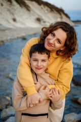 Fototapeta na wymiar family walk on the seashore in the cold season. happy mother and son hugging each other