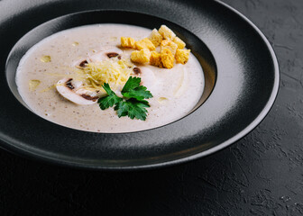 Creamy mushroom soup with champignons on black