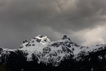 Aerial view of snowcap rocky mountains against dark gray cloudy sky