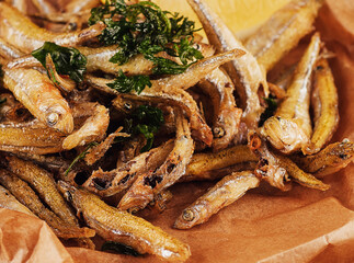 Hot fried smelt fish with salt and herbs on brown paper