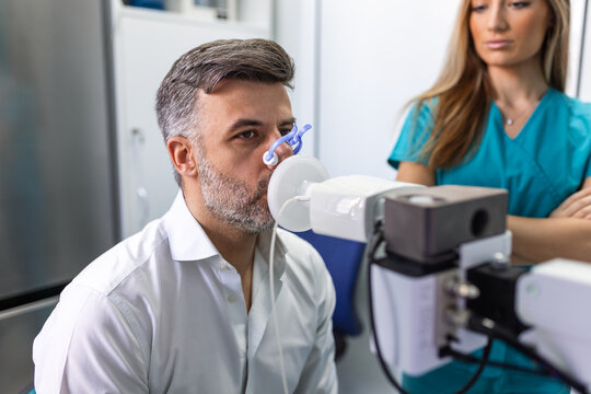 Adult man testing breathing function by spirometry having health problem. Diagnosis of respiratory function in pulmonary disease.