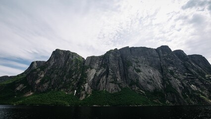 Low-angle shot of rocky mountains under the white sky.