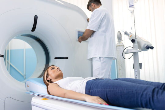 The patient lies on CT or MRI, the bed is moved inside the machine, scanning her body and brain under the supervision of a doctor, radiologist. In a medical laboratory with high-tech equipment.