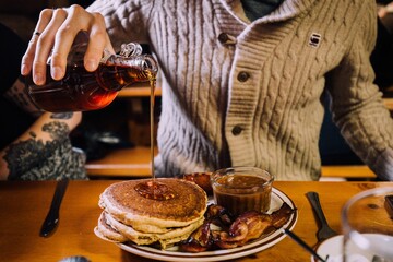 Plate with breakfast and a man pouring honey on pancakes
