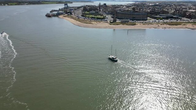 Small boat entering river mouth on sunny day at Wyre Estuary Fleetwood Lancashire UK