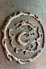 Golden statue of a traditional Chinese dragon on a rough stone wall