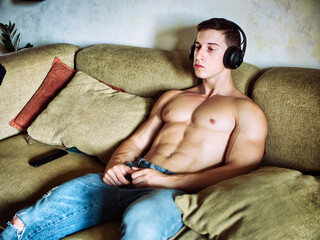 Male bodybuilder listening to music on sofa