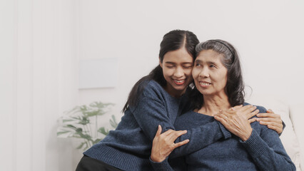 Hugging, kiss, love, Mother's day concept, young adult female daughter congratulate excited asian elderly mother at sofa with birthday anniversary, two generations family photo, real people.