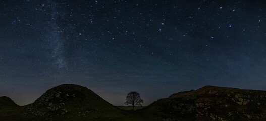 Scenic shot of the Sycamore gap under the starry sky in UK