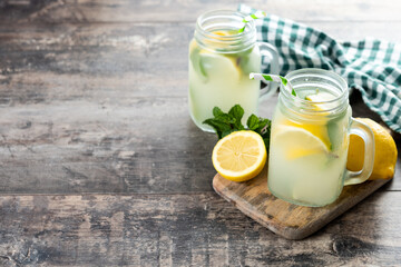 Lemonade drink in a jar glass and ingredients on wooden table. Copy space