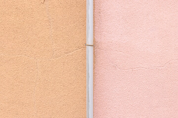 茶色とピンクに塗られた壁と屋根の排水パイプ