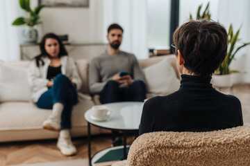 Back view of female psychologist having conversation with couple during therapy session