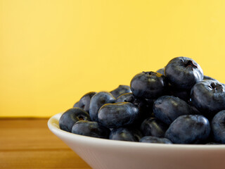 Freshly picked blueberries in a white vintage ceramic bowl. Selective focus, Free text space.