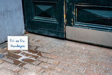 House entrance with a sign in Danish language standing on dry dog urine pleading dog owners to...