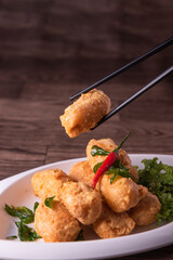 vegan deep fried golden beancurd tofu in salted egg yolk curry leaf pumpkin cream chilli vegetable on wood table asian chinese appetiser snack banquet halal food menu for restaurant