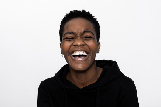 Photo of african american girl in good mood happy delighted woman over white background in studio isolated smiling laughing wearing casual black hoodie.