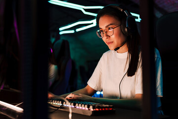Asian girl playing online video game in cybersport club