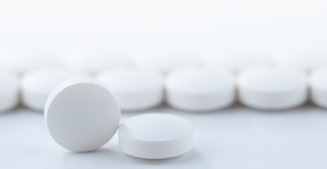 Close up white pills scattered on the table. Medicine, medical insurance or pharmacy concept