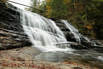 Obraz premium Landscape of a beautiful waterfall surrounded by rocks in a forest