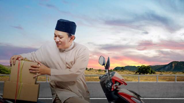 Asian Muslim man tying box on motorcycle prepare for mudik