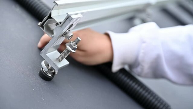 Close up view of competent engineer securing metal rails on a roof for ajusting solar panels on top of house. Professional installation of PV system.