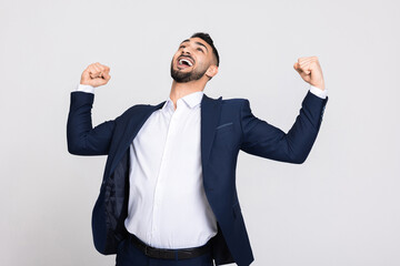 Happy strong buisness man wearing smart suit and white shirt standing over grey background in studio isolated showing strength biceps screaing celebrating good deal contract.