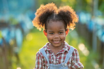 black african afro hair daughter of farmer family standing in green plantation greenhouse at sunset light. Woman little baby black afro walk in plantation greenhouse with rim light on hair