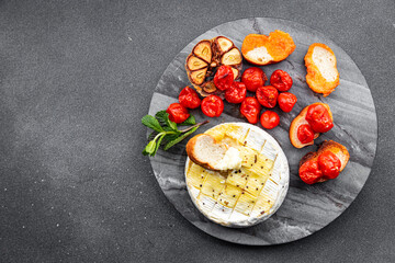 baked soft cheese Brie or Camembert tomato, garlic and herbs meal food snack on the table copy space food background rustic top view