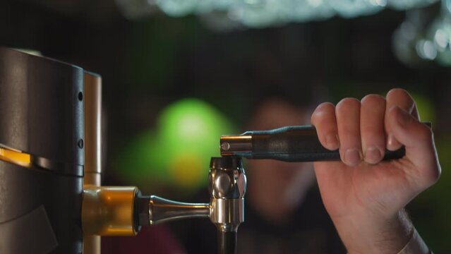 Barman turns beer pump lever to pour drink at counter in pub closeup. Bartender uses beverage dispenser working in brewery. Restaurant employee