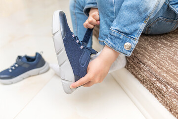 Children's hands on sneakers when putting on shoes. Close-up.