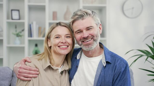 Webcam view. Close up of happy married couple hugging in living room at home looking at camera. Mature wife and husband cuddles, smile, rejoice looking at each other. Joyful moments of life together