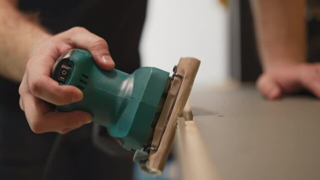 Carpenter polishes wooden furniture detail with manual tool in workshop closeup. Worker processes item at production plant. Handwork instrument