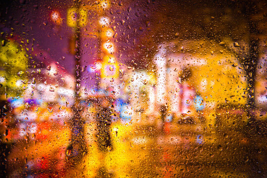 City view through a window on a rainy night,Rain drops on window with road light bokeh, City life in night in rainy season abstract background. Focus on drops on glass © Павел Мещеряков