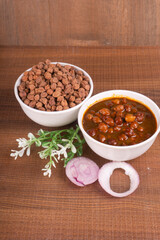 Chole masala or chana indian vegan food made of cooked chickpeas, tomatoes and cumin decorated with onion rings.