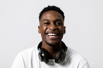 Happy delighted cheerful african american black guy man wih black headphones standing over grey white background in studio isolated smiling in good mood posing for banner advetisement concept.