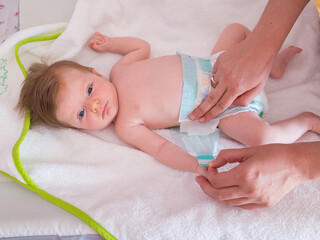 Mother changing the nappy or diaper of an eight week old baby girl