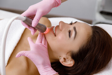 Cosmetology service, Facial treatment, Rejuvenation treatment, female cosmetologist is performing a facial diagnostic procedure