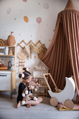 children's room in scandinavian style. canopy in the interior, storage of toys, a little girl plays