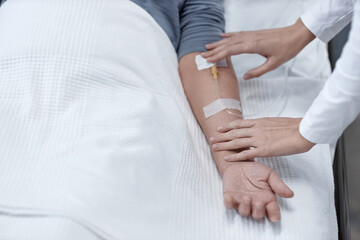 Close-up of nurse making iv drip for senior patient during treatment in hospital