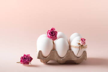 Composition with Easter eggs and eco-decor of dried roses on a beige background.
