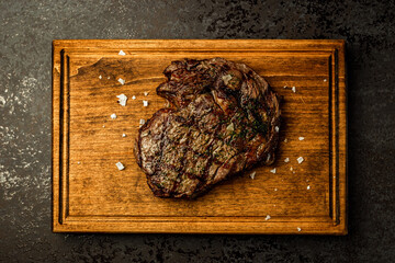 Top view of boneless ribeye steak served on a wooden board in a restaurant - 591465714