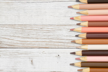 Multiculture skin tone color pencils crayons background on weathered wood
